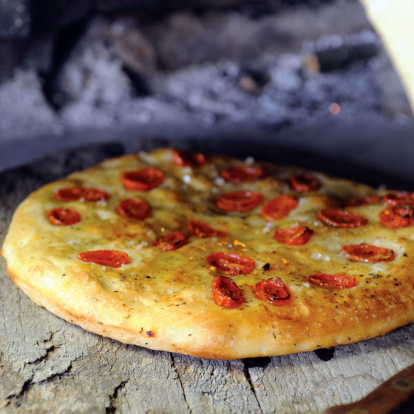 Step 9: the baked focaccia, pictured in front of an open wood fire oven