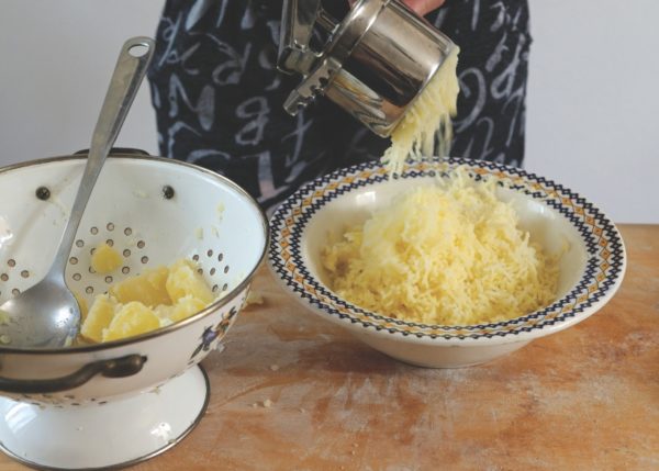cooked potatoes in colander and ricer