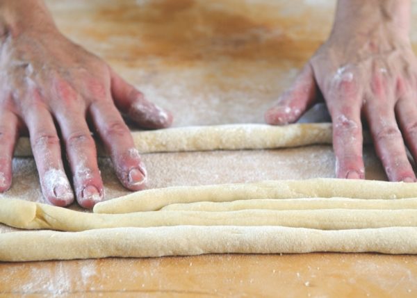 rolling chunks of dough into long thin sausages
