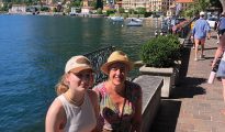 Lorenza and her daughter sat on a wall lakeside in Menaggio