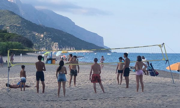 teens playing volleyball on a beach