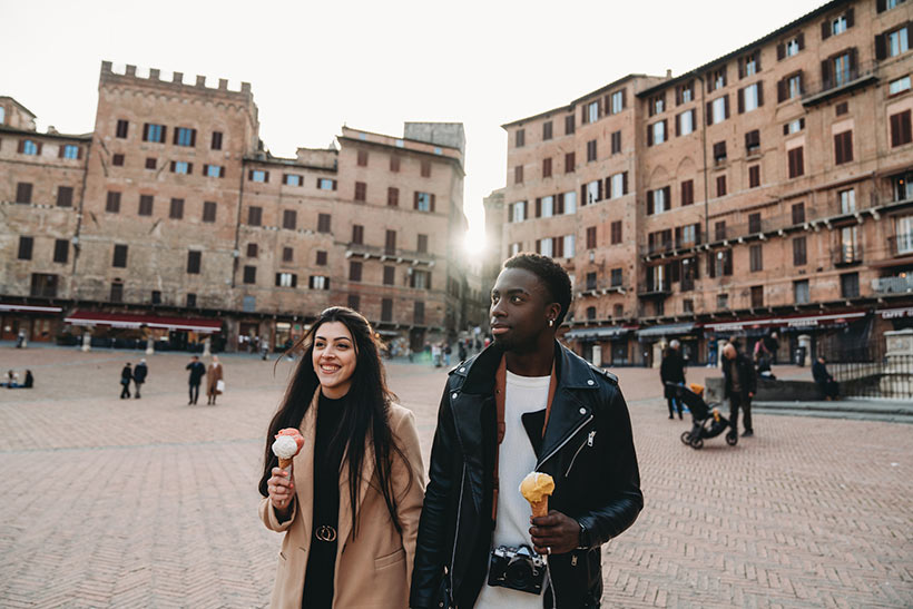 Couple walking in plaza in Siena with gelato