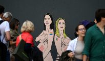 Pedestrians look at a mural painting made by Italian artist and activist aleXsandro Palombo, depicting Prime Minister Giorgia Meloni (R) and Democratic Party (PD) Secretary Elly Schlein (L) naked and pregnant in reference to the ongoing debate over surrogacy in the country