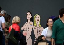 Pedestrians look at a mural painting made by Italian artist and activist aleXsandro Palombo, depicting Prime Minister Giorgia Meloni (R) and Democratic Party (PD) Secretary Elly Schlein (L) naked and pregnant in reference to the ongoing debate over surrogacy in the country