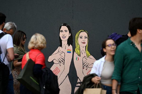 Pedestrians look at a mural painting made by Italian artist and activist aleXsandro Palombo, depicting two women; Prime Minister Giorgia Meloni (R) and Democratic Party (PD) Secretary Elly Schlein (L) naked and pregnant in reference to the ongoing debate over surrogacy in the country