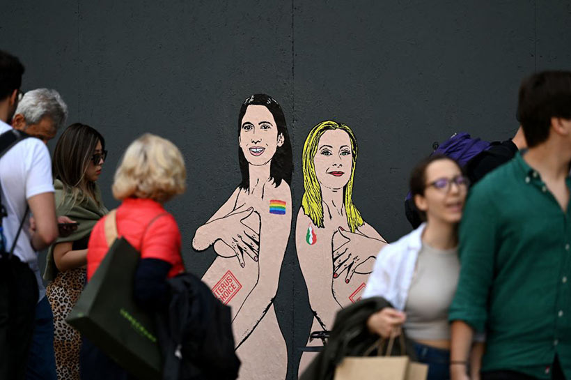 Pedestrians look at a mural painting made by Italian artist and activist aleXsandro Palombo, depicting Prime Minister Giorgia Meloni (R) and Democratic Party (PD) Secretary Elly Schlein (L) naked and pregnant in reference to the ongoing debate over surrogacy in the country