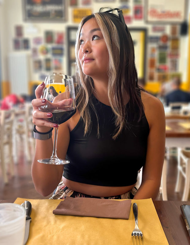Young woman looks away while holding wine at a wine tasting in Bologna, Italy
