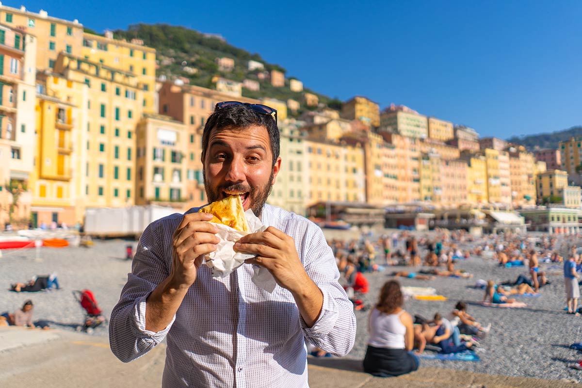 Foodie genoa - happy tourist eating focaccia on ligurian beach