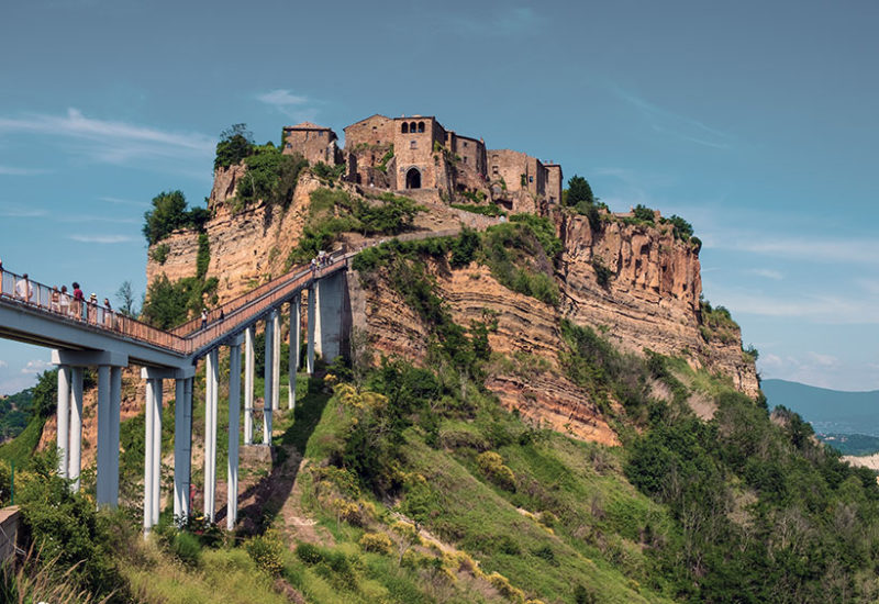 Panoramic view of Italian ghost town of Civita di Bagnoregio with a connecting bridge and surrounding hills and valleys of Lazio region