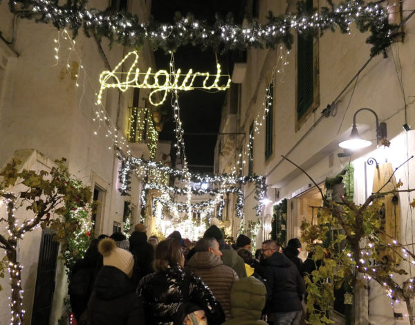 Narrow street with crowd of people. Lit with christmas decorations