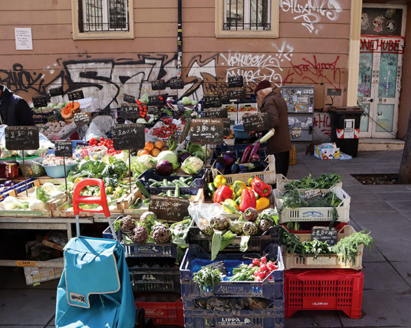 Pigneto market in rome, outdoor market stalls with graffiti on building behind