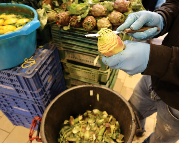 gloved hands preparing artichokes on stall