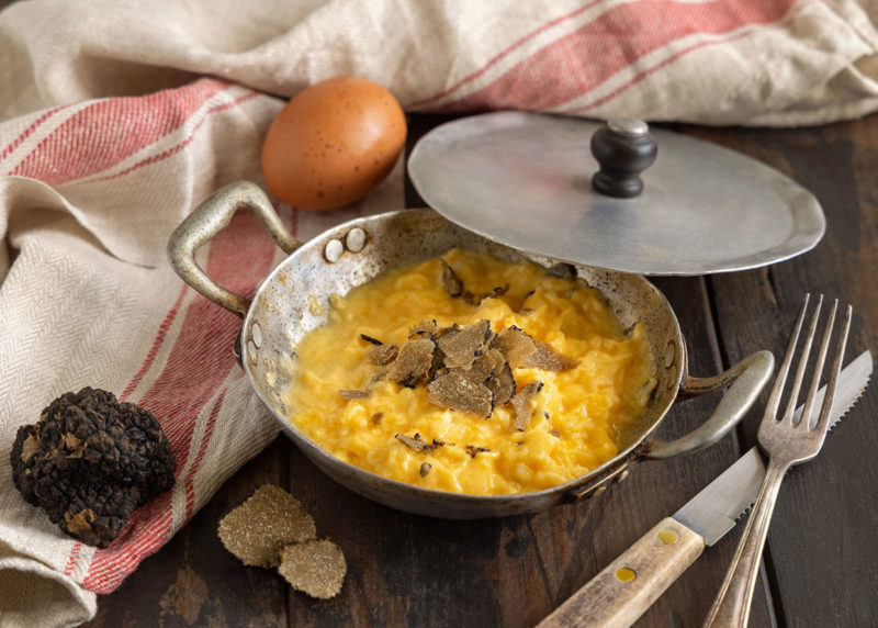 Scrambled eggs with fresh black truffles from Italy served in a frying pan