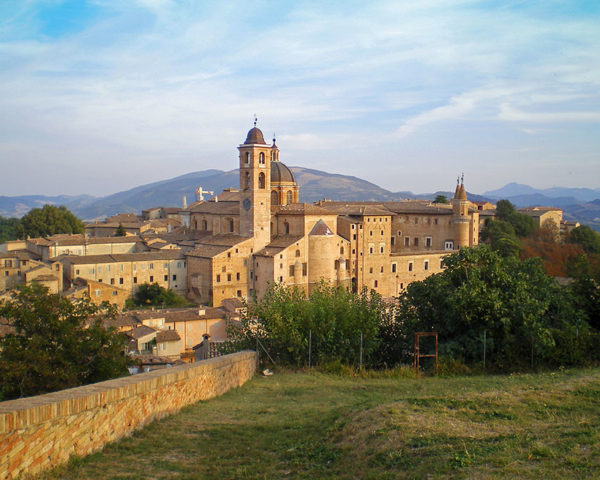 view of the renaissance town of Urbino in the Le Marche region of Italy showing the historical Ducal Palace and the wonderful hilly and mountainous landscape beyond