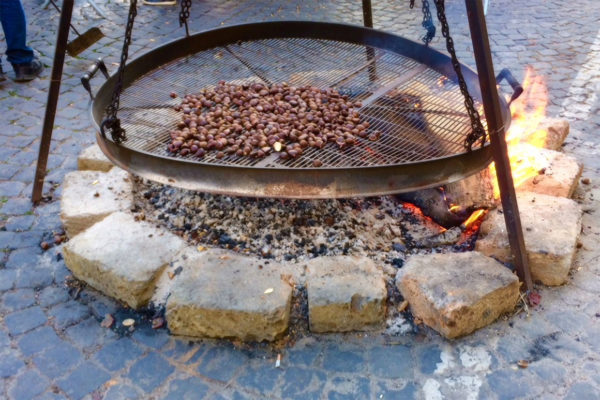 Chestnuts roasting on large round pan/brazier on open fire outdoors